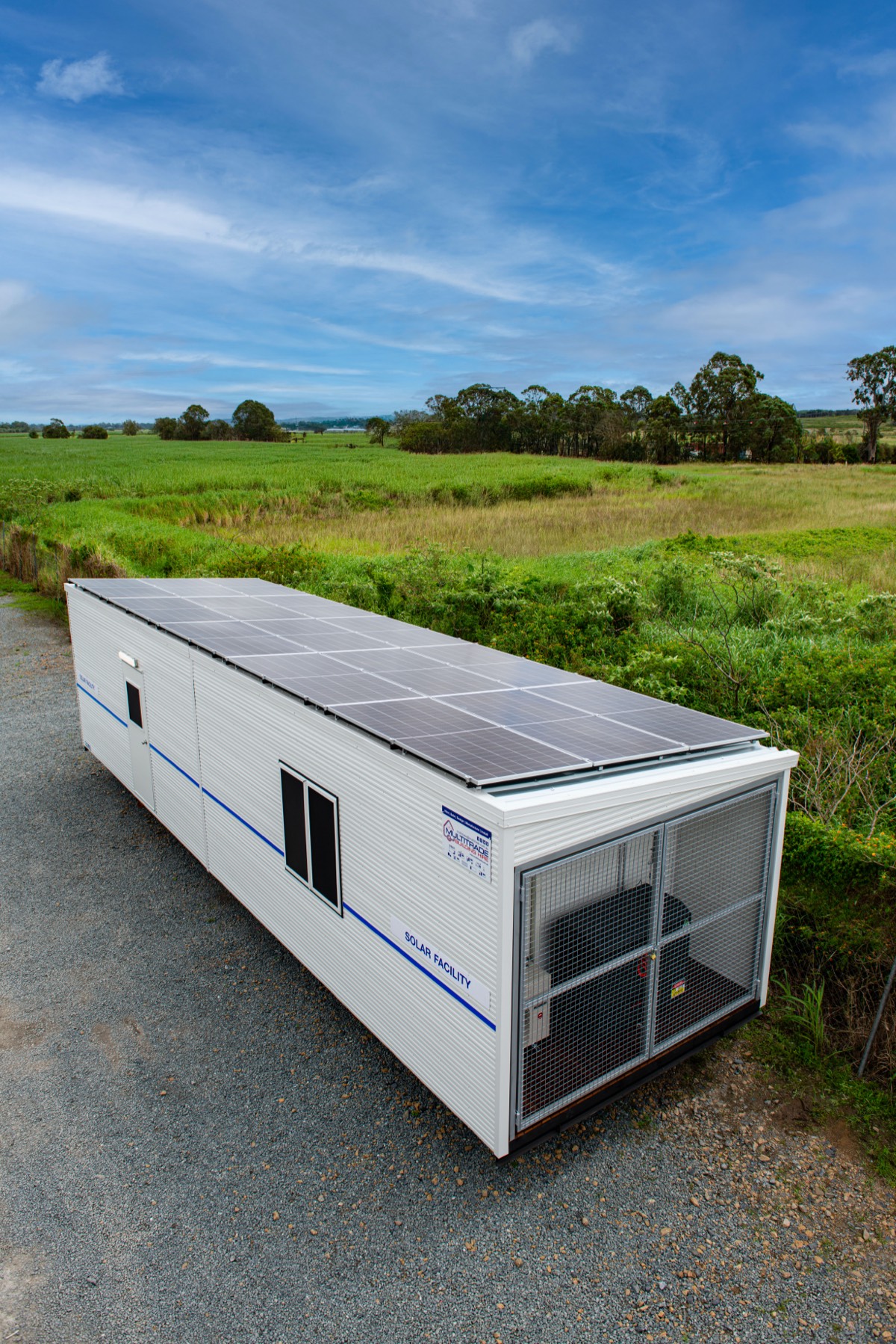 Multitrade solar-powered portable building with blue sky and green fields